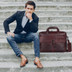Professional man carrying the brown leather briefcases for men by the top handle.